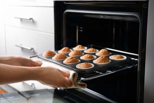 Mani che tolgono dal forno teglia con muffins