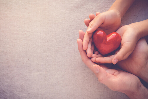 Mani che tengono un cuore rosso