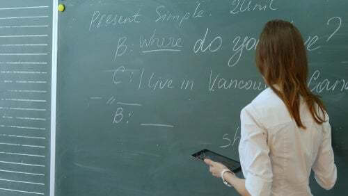 Ragazza che svolge un esercizio di lingua inglese alla lavagna.
