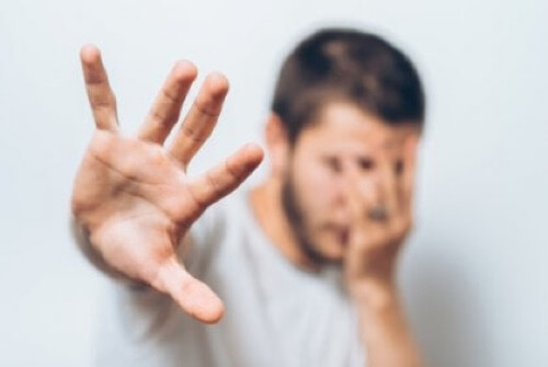 Uomo spaventato che si copre il viso