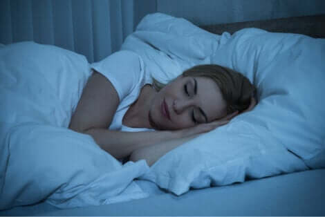 Donna addormentata tra lenzuola bianche.