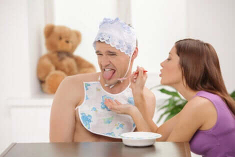 Donna che imbocca uomo vestito da neonato che soffre di infantilismo parafilico.