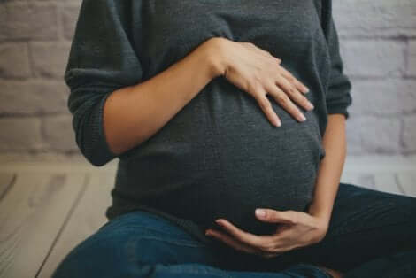 Domma incinta si accarezza la pancia con le mani.
