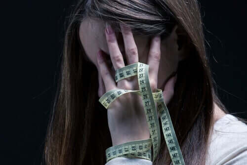 Ragazza anoressica si misura con un metro.