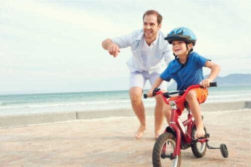 Padre che gioca con il figlio in bicicletta.