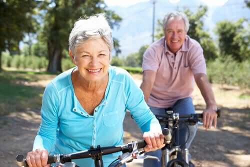 Coppia di persone anziane che fanno un giro in bicicletta in campagna.