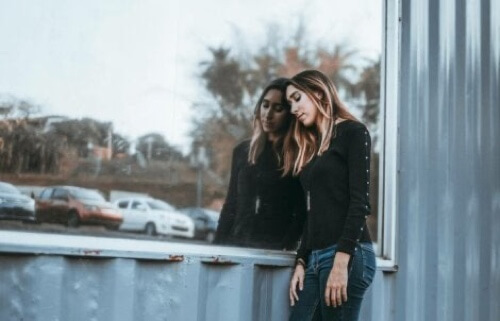 Ragazza appoggiata a un vetro.