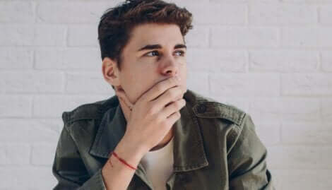 Ragazzo pensieroso con mano sulla bocca.