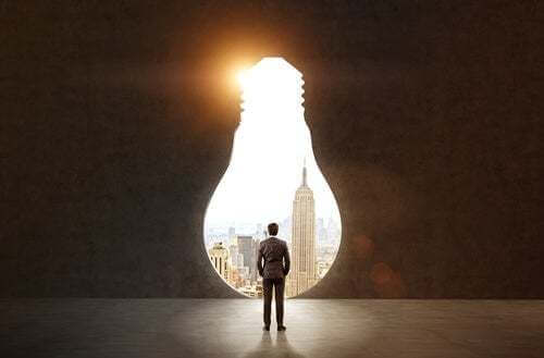 Uomo di fronte a una porta sul mondo a forma di lampadina.