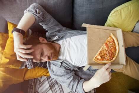 Uomo che mangia la pizza davanti alla televisione.