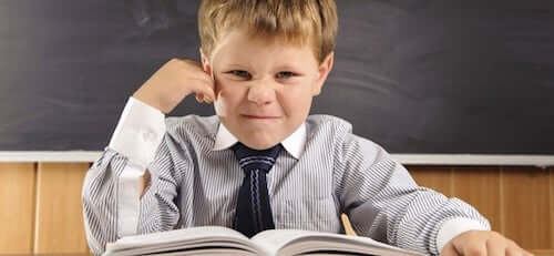 Bambino adirato perché deve leggere un libro.
