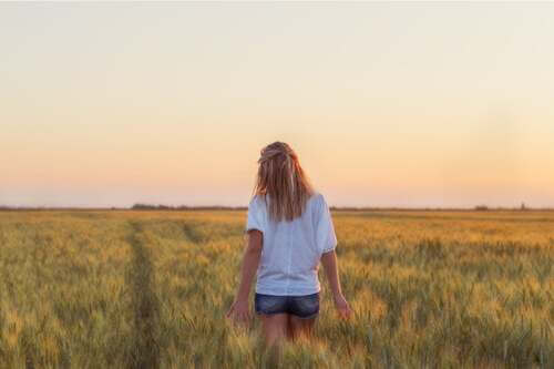 Donna di spalle in un campo di grano.