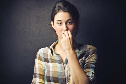 Donna dubbiosa che si mangia le unghie.