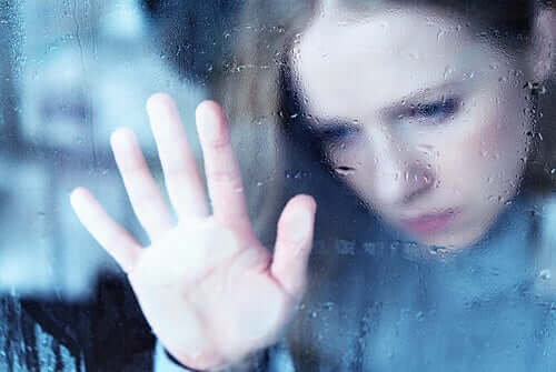Ragazza triste che guarda dalla finestra.