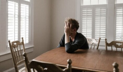 Ragazzo esausto poggiato a un tavolo.