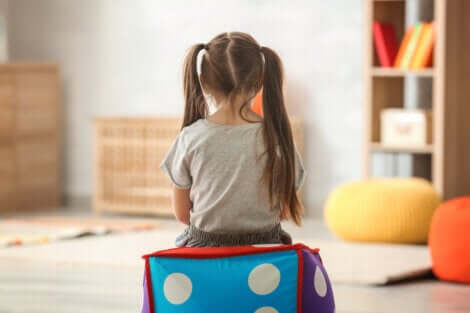 Bambina seduta di spalle sopra un cubo gonfiabile.