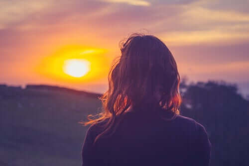 Donna di spalle che guarda il tramonto.