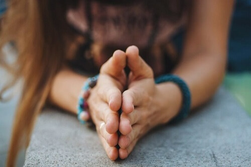 Ragazza con le mani giunte che esprime gratitudine.