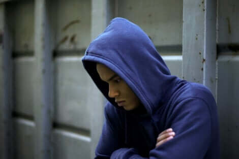 Ragazzo pensieroso che indossa una felpa blu con cappuccio.