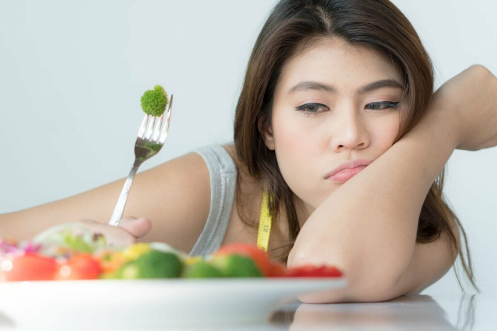 Donna con fobie alimentari che cerca di mangiare le verdure.