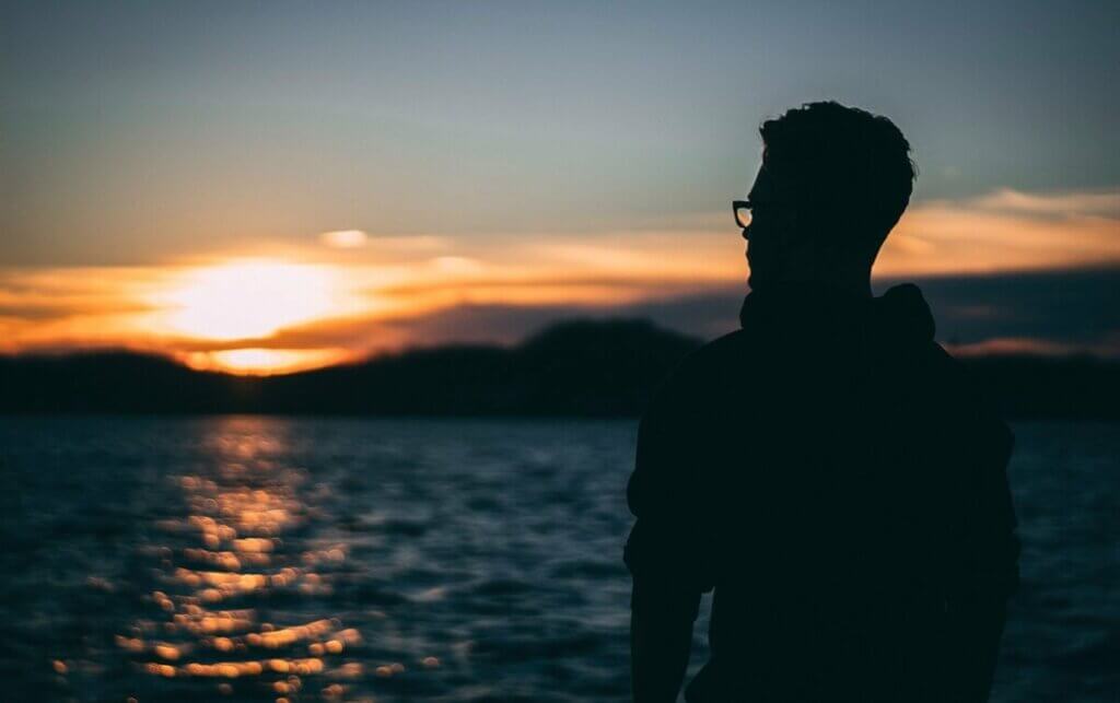 Ragazzo con occhiali davanti al mare.