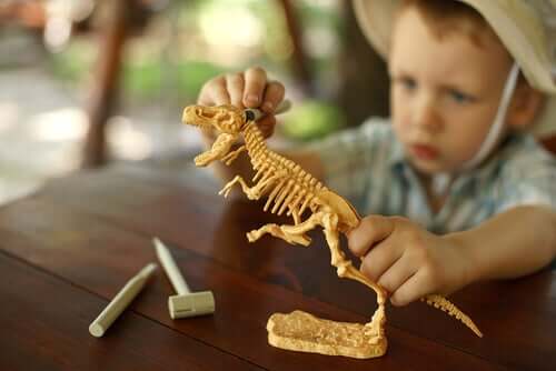 Bambino gioca con modellino di dinosauro.