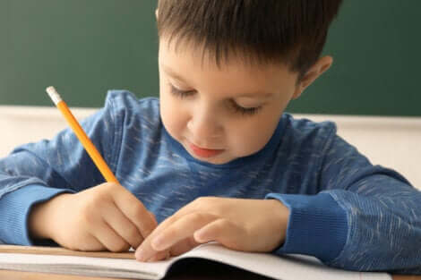 Bambino scrive su quaderno con matita.