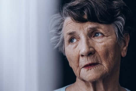 Donna anziana con sguardo assente e morbo di Alzheimer.