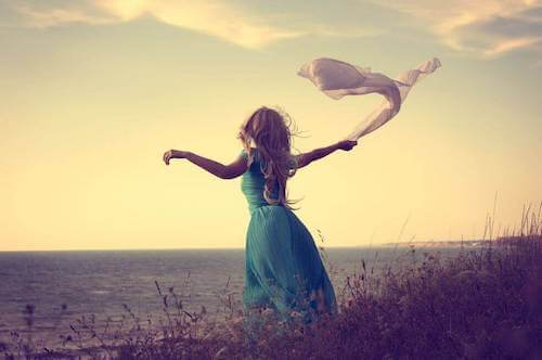 Donna che guarda il mare con un fazzoletto svolazzante in mano.