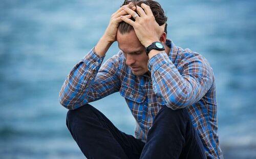 Uomo deluso che si regge la testa.