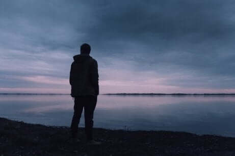 Uomo di spalle davanti al mare con depressione esistenziale.