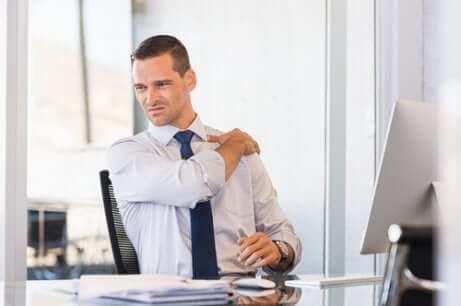Uomo in ufficio con tensione muscolare alla spalla.