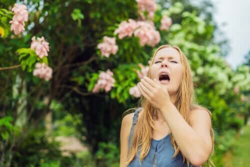 Donna che starnutisce perché è allergica al polline dei fiori.