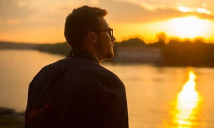 Ragazzo che osserva il tramonto sul fiume.