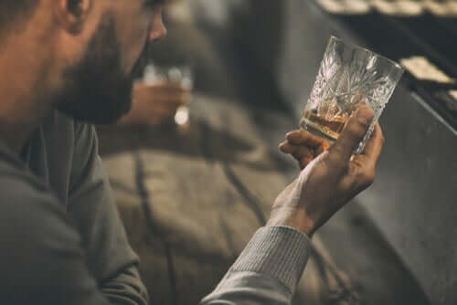 Persona che guarda bicchiere con liquore.