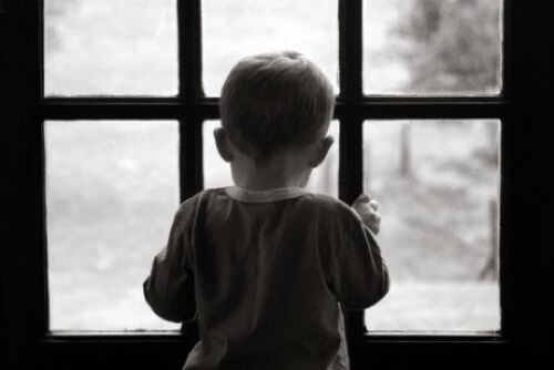 Bambino che guarda dalla finestra.