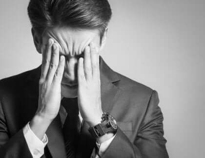 Uomo preoccupato con le mani sul volto.