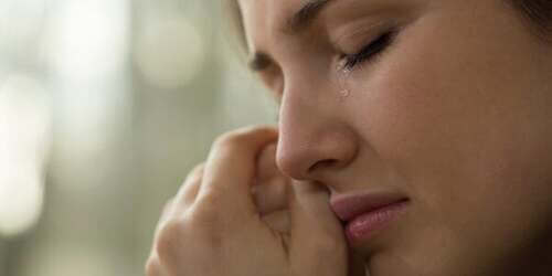 Donna che piange asciugandosi le lacrime.