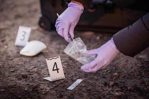 Persona sulla scena del crimine che raccoglie delle prove.
