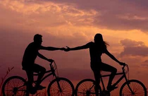 Tenersi per mano in bici al tramonto.