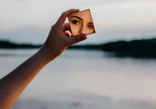 Donna che si guarda allo specchio vicino ad un lago.