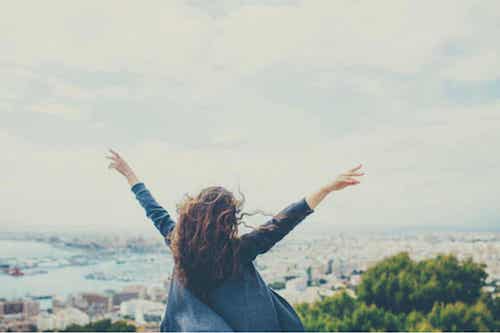 L'importanza di piacersi e accettarsi. Donna felice con le braccia verso il cielo.