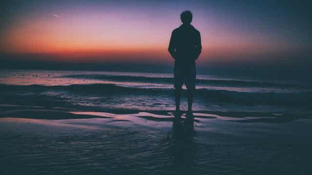 Uomo di fronte al tramonto sul mare.