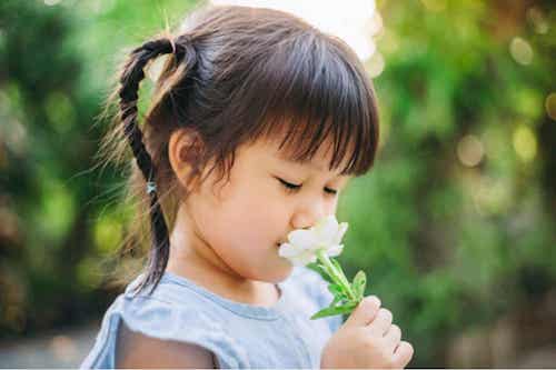 Bambina che odora un fiore.