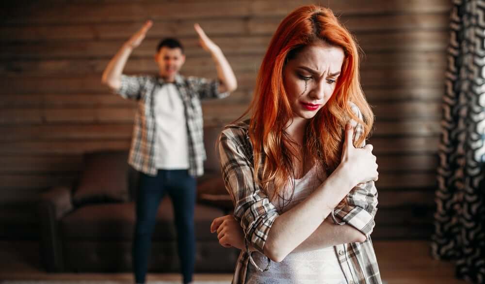 Riconoscere un rapporto abusivo e donna maltrattata che piange e il suo partner che le urla contro.